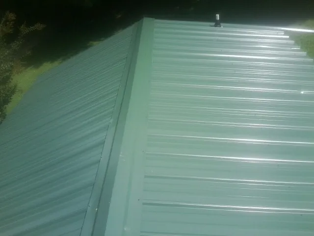 New green metal panels meeting at the ridge of a roof — Flat Roof Repair work by our crew in Marshall