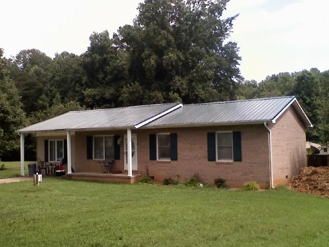 Gray metal roof on a brick ranch house with a side carport in Marshall
